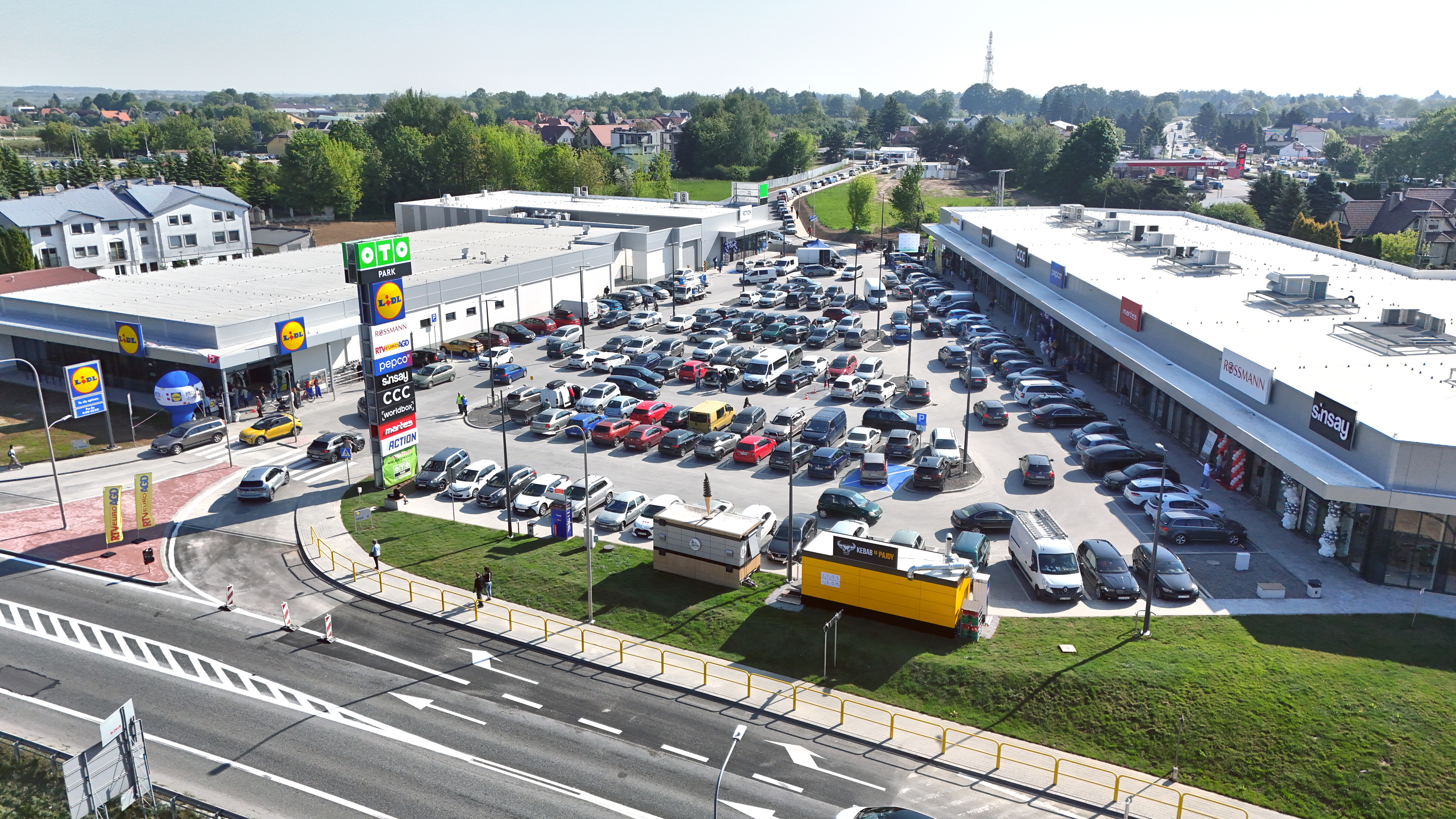 Budynek parki handlowego OTO Park w Sandomierzu, widoczny od frontu z samochodami na parkingu.